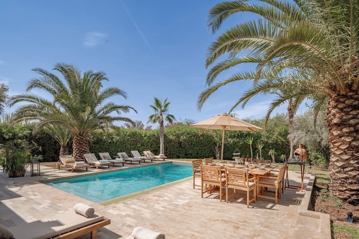 Piscine Villa Aima avec table repas en bois et palmiers Marrakech